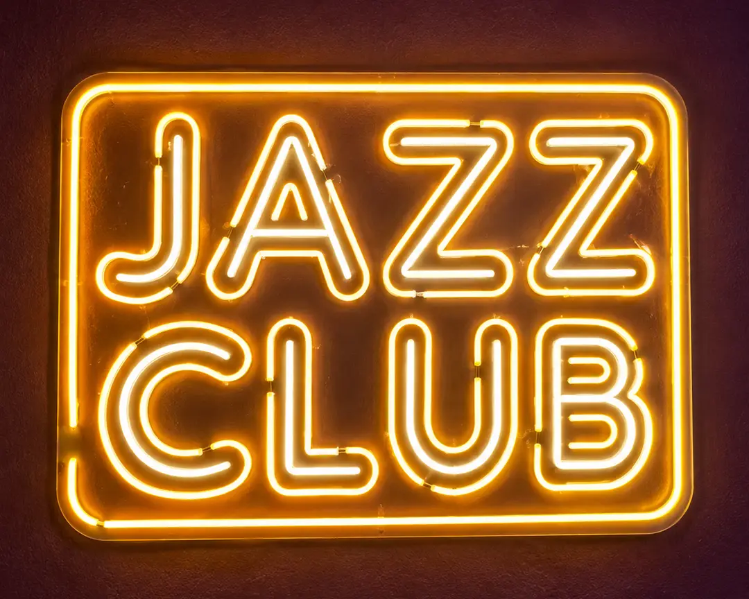 لافتة JAZZ CLUB النيون تتوهج بلون ذهبي على جدار داكن