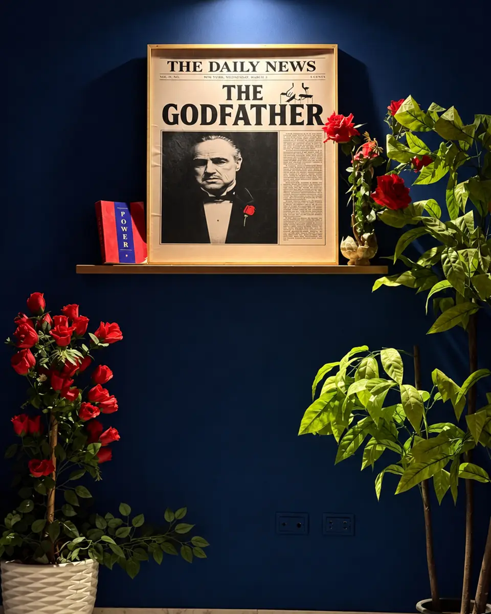 صورة جريدة The Godfather في إطار بين النباتات والورد الأحمر